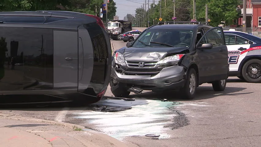 A damaged vehicle at the roadside with police vehicles behind it